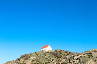 Building on rock against clear blue sky