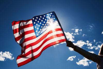 Waving usa flag in hand against blue sky
