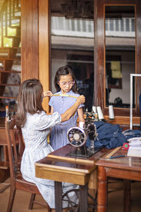 Rear view of tailor taking measurement in workshop