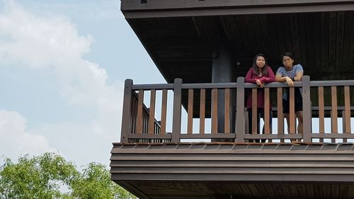 Low angle view of children on wooden structure against sky