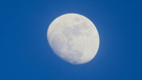 Low angle view of moon in blue sky