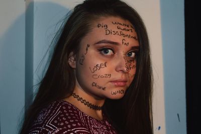 Portrait of young woman with text on face at home