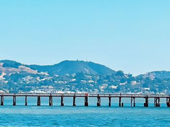 Pier over sea against clear blue sky