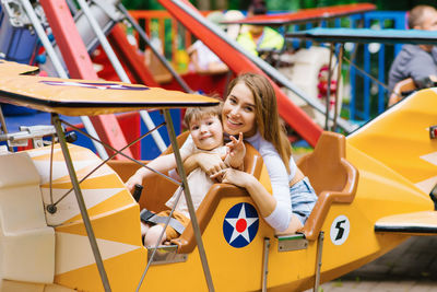 Mom and her little son's family weekend at an amusement park. a mother and her boy ride bright
