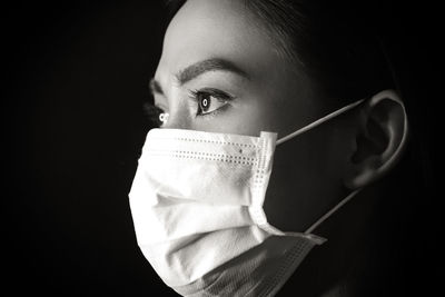 Close-up portrait of young woman against black background