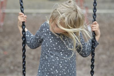 Girl standing on swing in playground