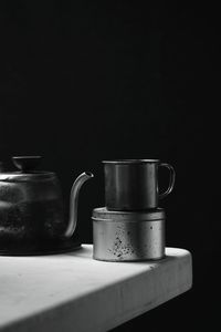 Close-up of teapot and tin cup on table 