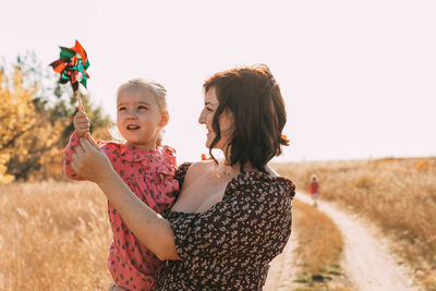 Mom shows little daughter how to use a windmill on outdoor. esg and clean energy concept.