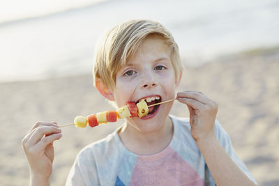 Boy eating fruit kebab