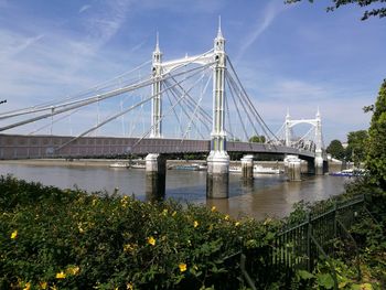 Suspension bridge over river against sky