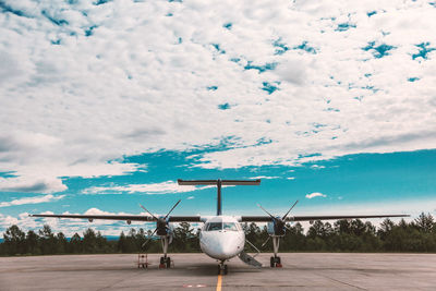 Airplane flying over airport runway against sky