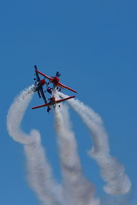 Low angle view of airplane flying against blue sky