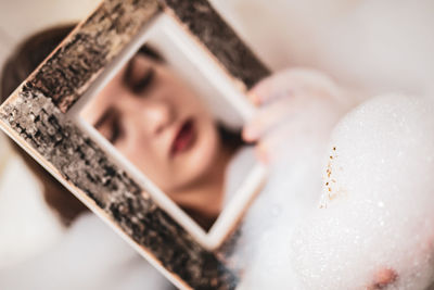 Close-up of woman holding picture frame while bathing