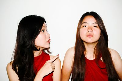 Woman pointing at female friend against white background