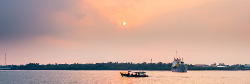 Sailboats in sea against sky during sunset