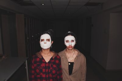 Portrait of friends with facial mask standing in passage