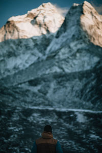 Rear view of man against rocky mountains during winter