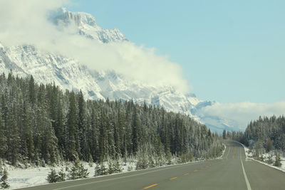 Road by snowcapped mountains against sky