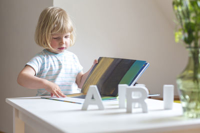 Girl reading book on table at home