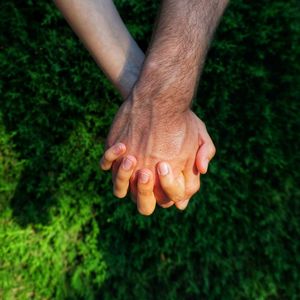 Low section of unrecognizable couple holding hands on grass
