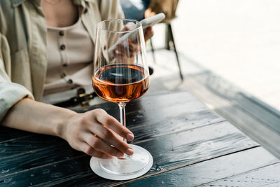 Midsection of woman holding wine glass on table at restaurant