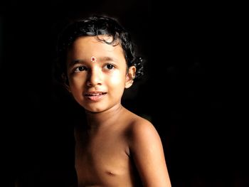 Portrait of cute boy against black background