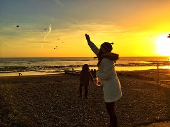 Silhouette of people on beach at sunset