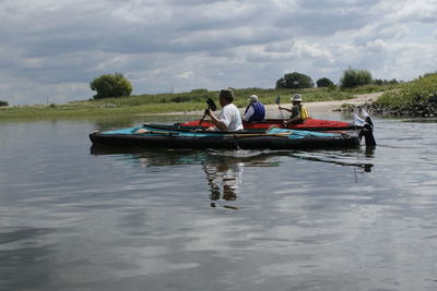 People in boat on lake against sky