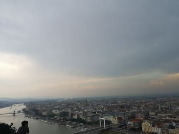 High angle view of buildings by river against sky during sunset