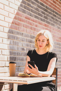 Beautiful woman using mobile phone while sitting at cafe