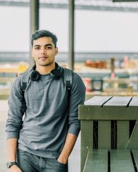 Portrait of young man standing against railing