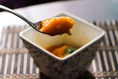 Close-up of mango sorbet on spoon above bowl
