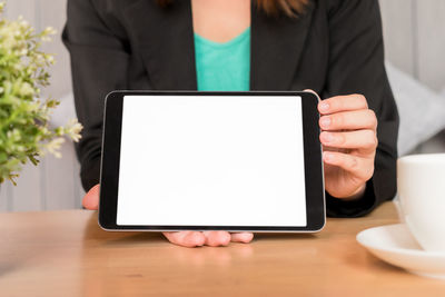 Midsection of man holding smart phone on table