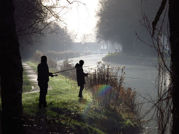 People standing on land by trees