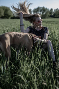 Young woman with dog sitting on grassy field