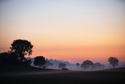 Dawns early light illuminates morning ground fog on country farm scene