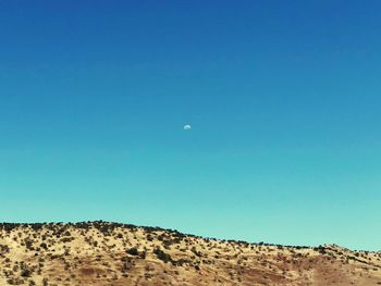 Low angle view of desert against clear blue sky