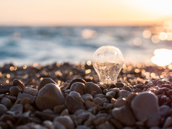 Close-up of pebbles on beach against sky during sunset