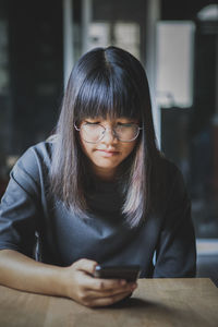 Young woman using mobile phone at table