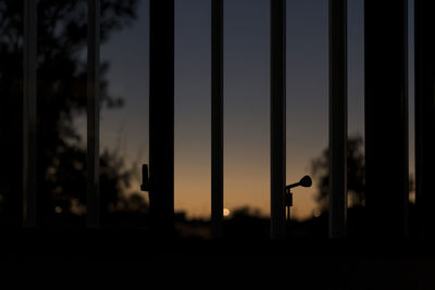 Close-up of silhouette glass window against sky at sunset