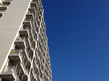 Low angle view of apartment building against clear blue sky