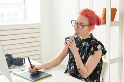 Red head woman smoking electronic cigarette at office