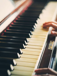 Close-up of hands playing piano in home