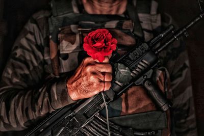 Midsection portrait of a soldier holding red roses