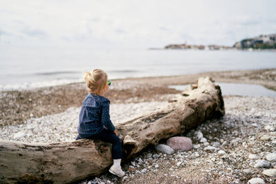 Side view of boy standing on beach against sky