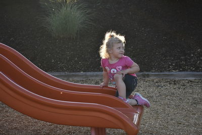 Cute girl kneeling on slide in playground