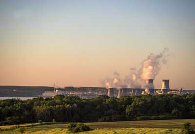 Cooling towers at nuclear power station against sky during sunset