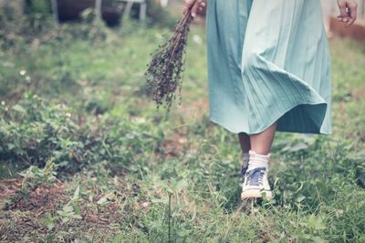 Low section of woman holding umbrella on field