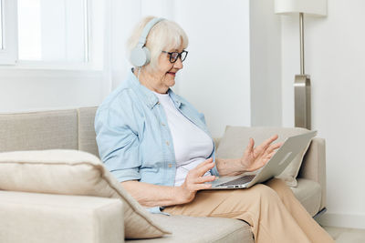 Young woman using laptop while sitting on sofa at home