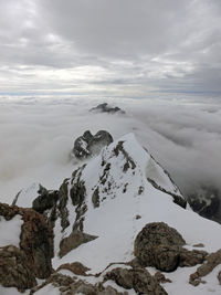 Rocks on snowcapped mountain against sky